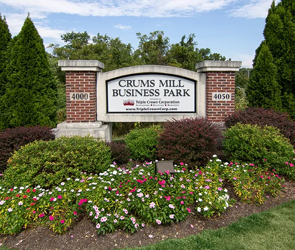 a sign for crums mill business park is surrounded by flowers