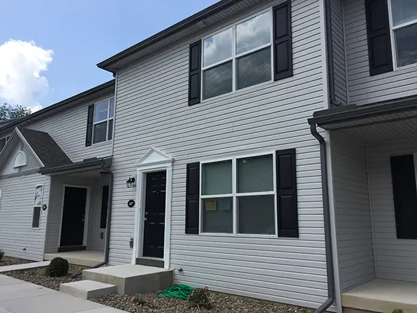 a white house with black shutters and a green hose in front of it