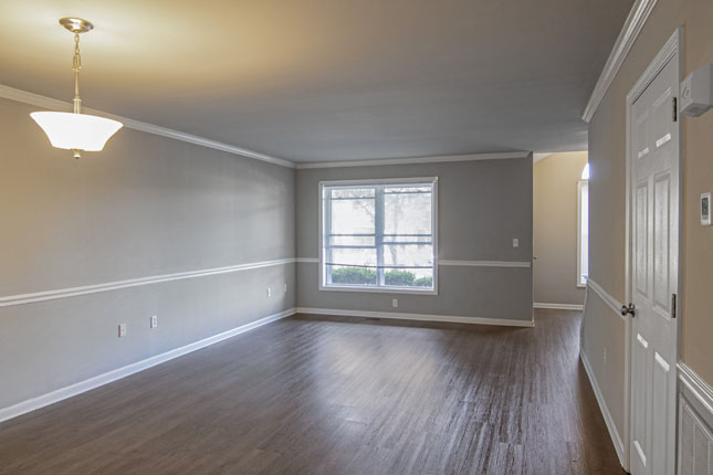 an empty living room with hardwood floors and gray walls
