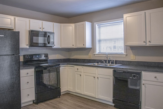 A Kitchen with White Cabinets Black Appliances and a Window