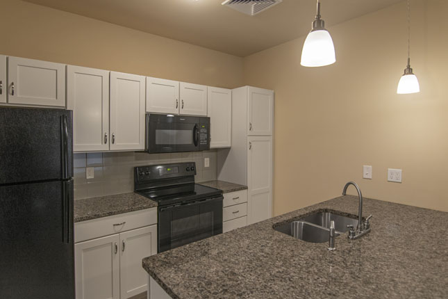 a kitchen with granite counter tops and a black refrigerator