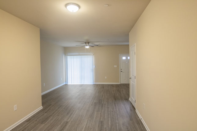 an empty hallway with hardwood floors and a ceiling fan