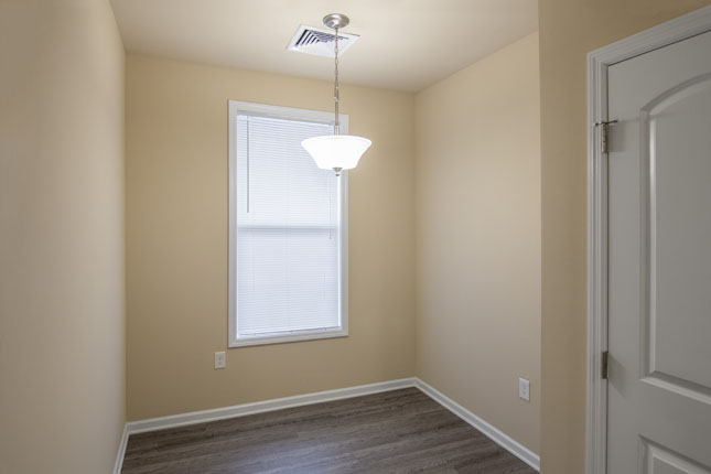 an empty room with a window and a light hanging from the ceiling