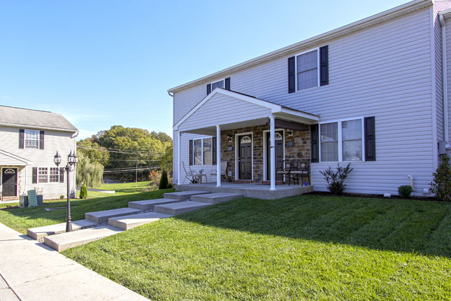 a white house with black shutters sits on a lush green lawn