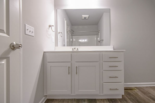 a bathroom with white cabinets and a large mirror