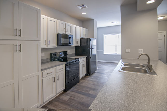 a kitchen with white cabinets black appliances and a sink