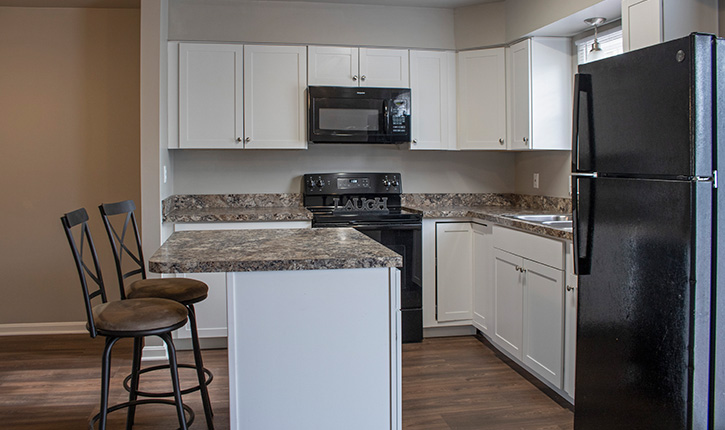 a kitchen with white cabinets and a black refrigerator