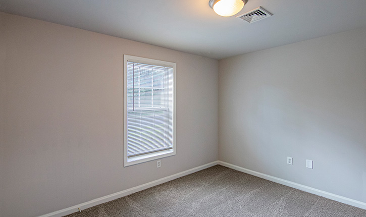 an empty bedroom with a window and blinds