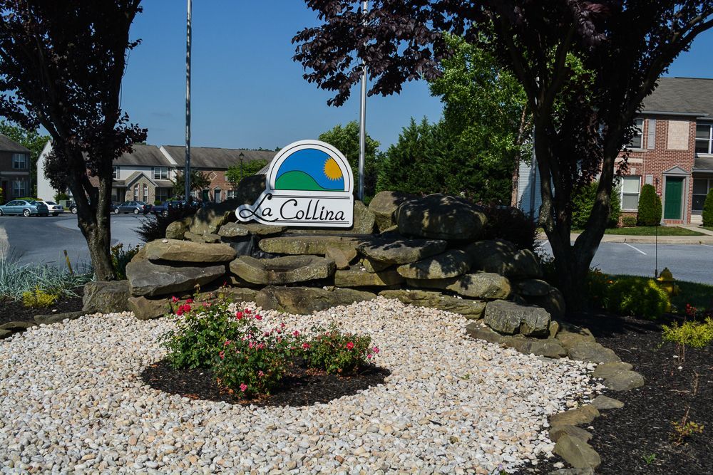 a sign for la collina sits on a pile of rocks