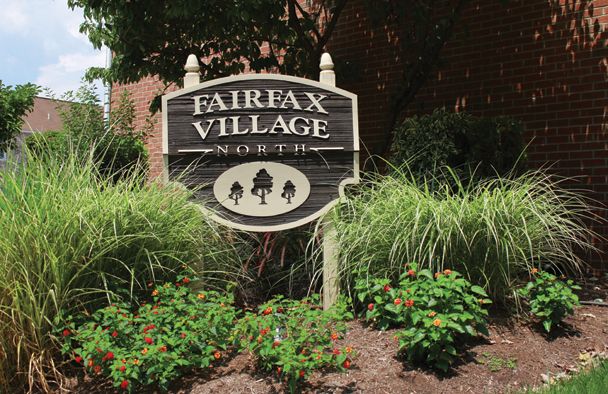 a sign for fairfax village north is in front of a brick building