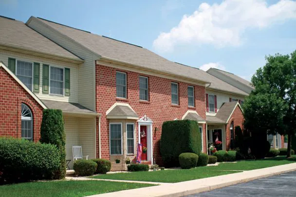 a row of brick houses with white siding and green shutters