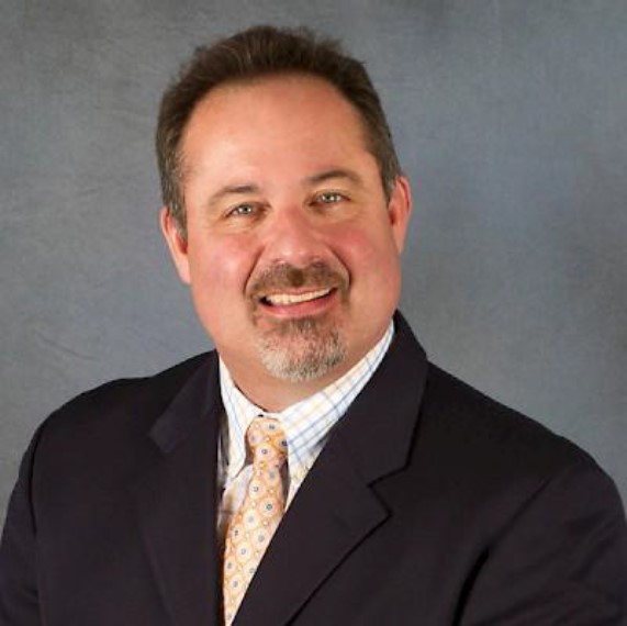 a man in a suit and tie is smiling for the camera