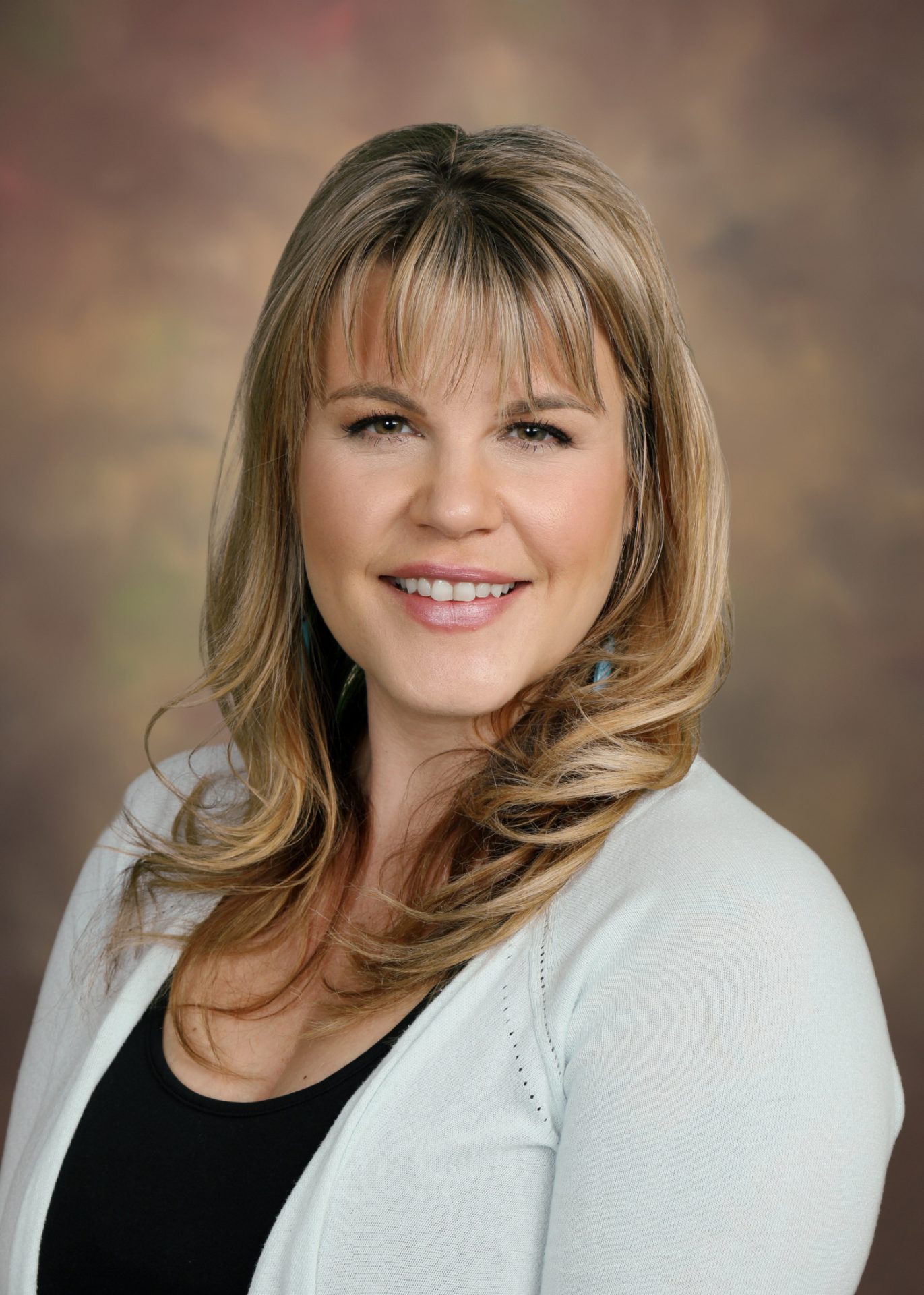 a woman in a white sweater smiles for the camera