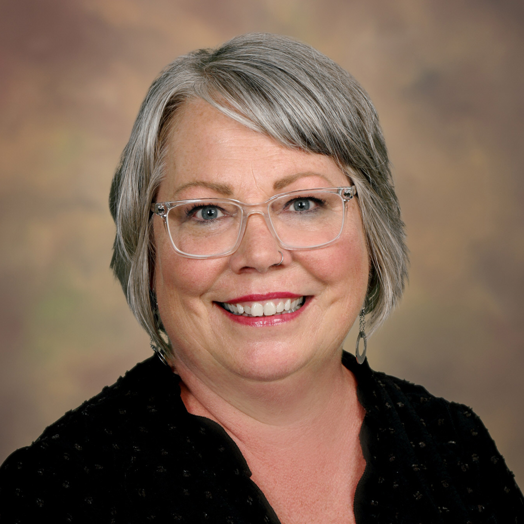 a woman wearing glasses and a black shirt smiles for the camera